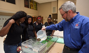 students gathered around a teacher demonstrating a science project